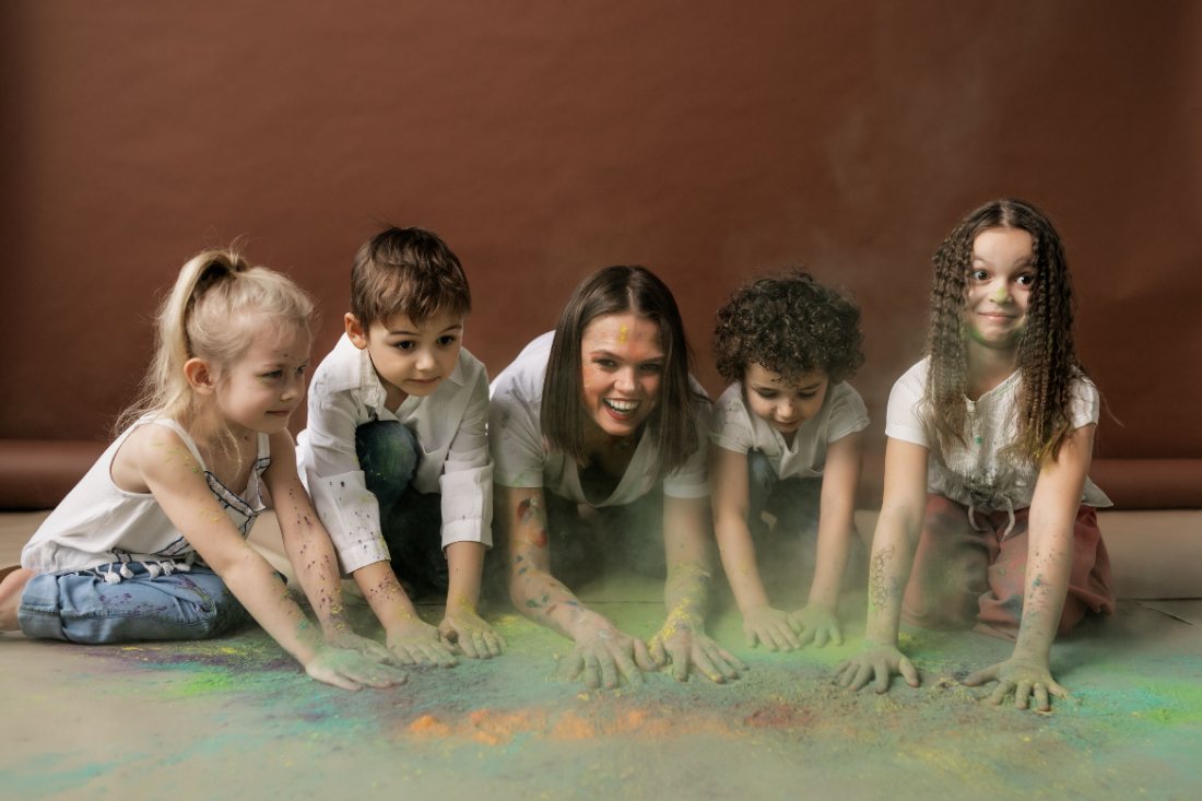 Children and a program leader laughing together during a colour-powder activity